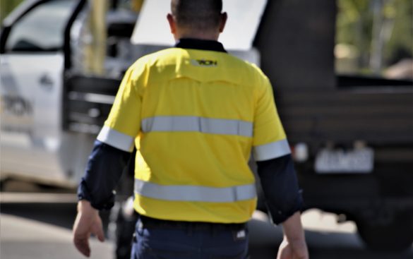 Orion electrician in yellow workwear beside a work vehicle